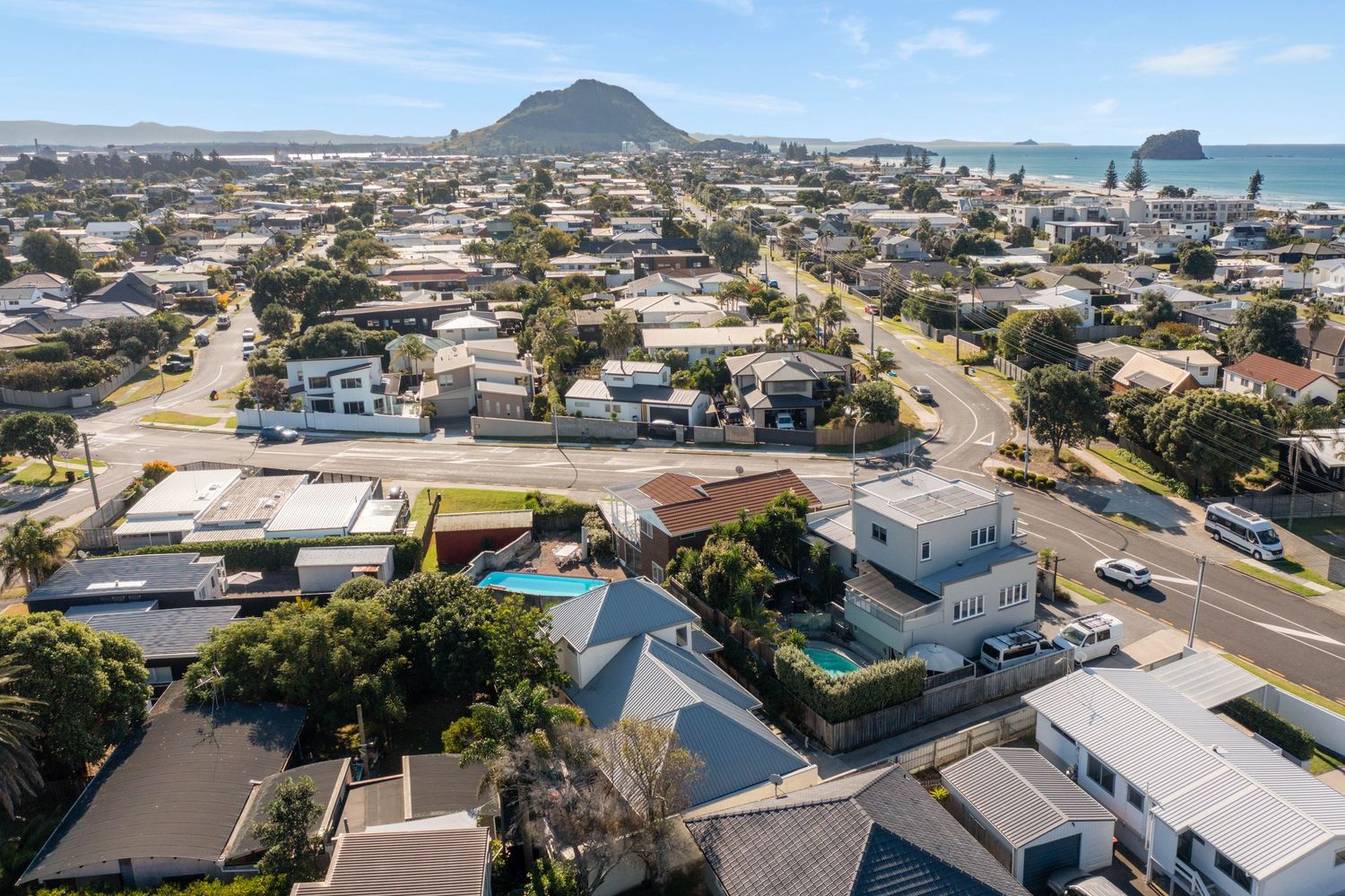 Birds eye view of coastal neighborhood with Mount Maunganui and Moturiki Island in the background.