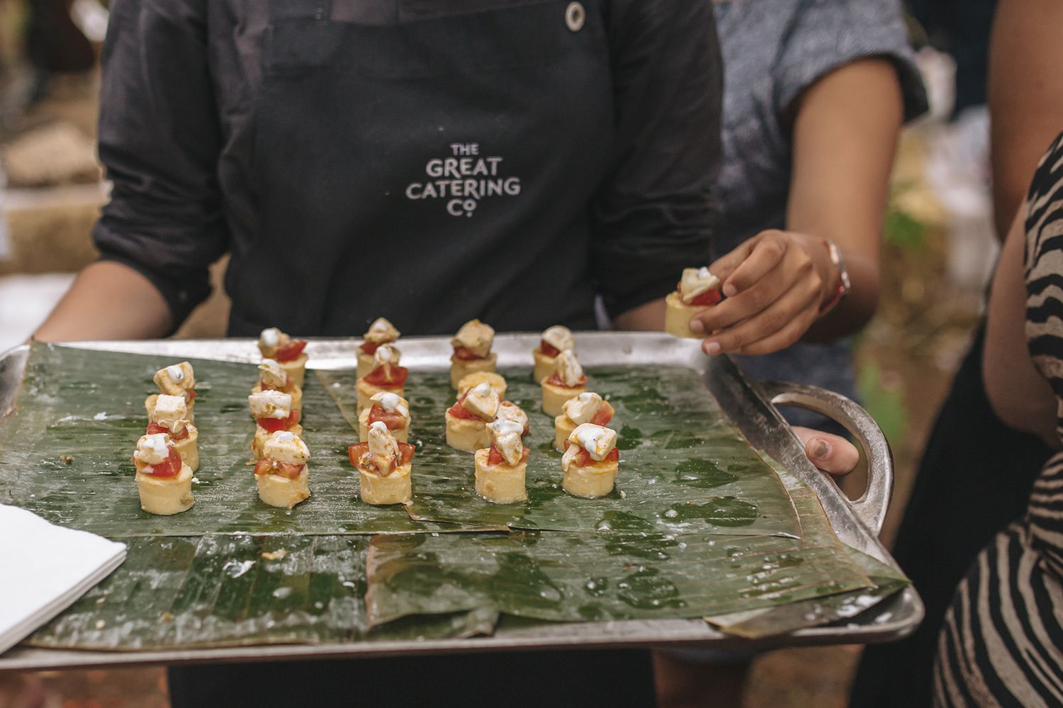 Elegant appetizers displayed on stone serving platters at outdoor wedding reception.