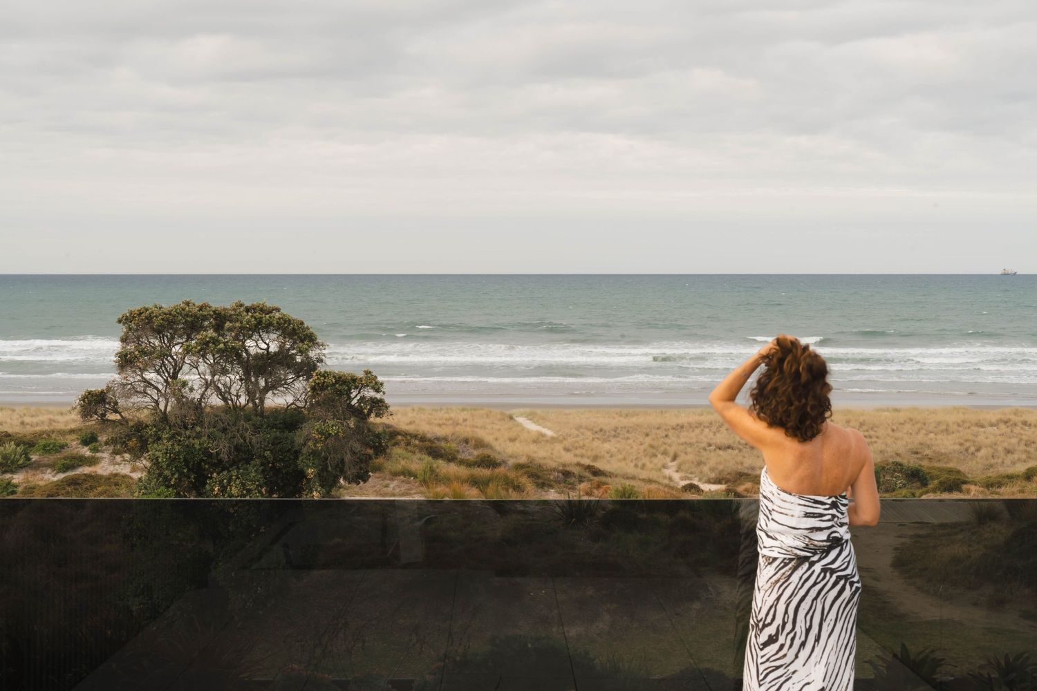 Oceanfront terrace with glass barriers offering panoramic views of beach and coastline.