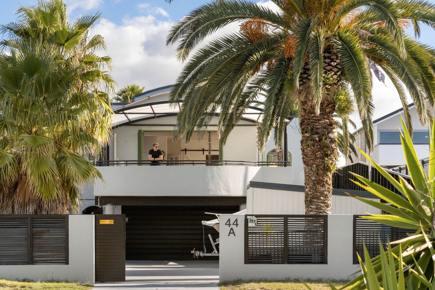 Tropical villa exterior with modern architecture and palm trees framing a white contemporary design.