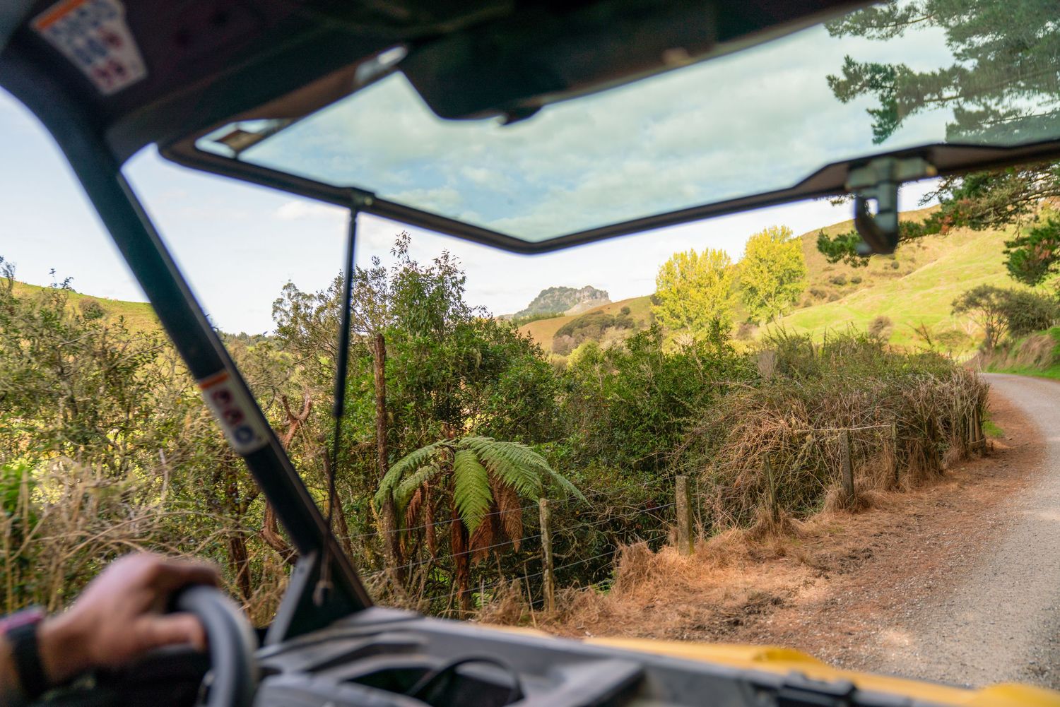 Dashboard view through car windshield of winding rural road through hilly countryside.