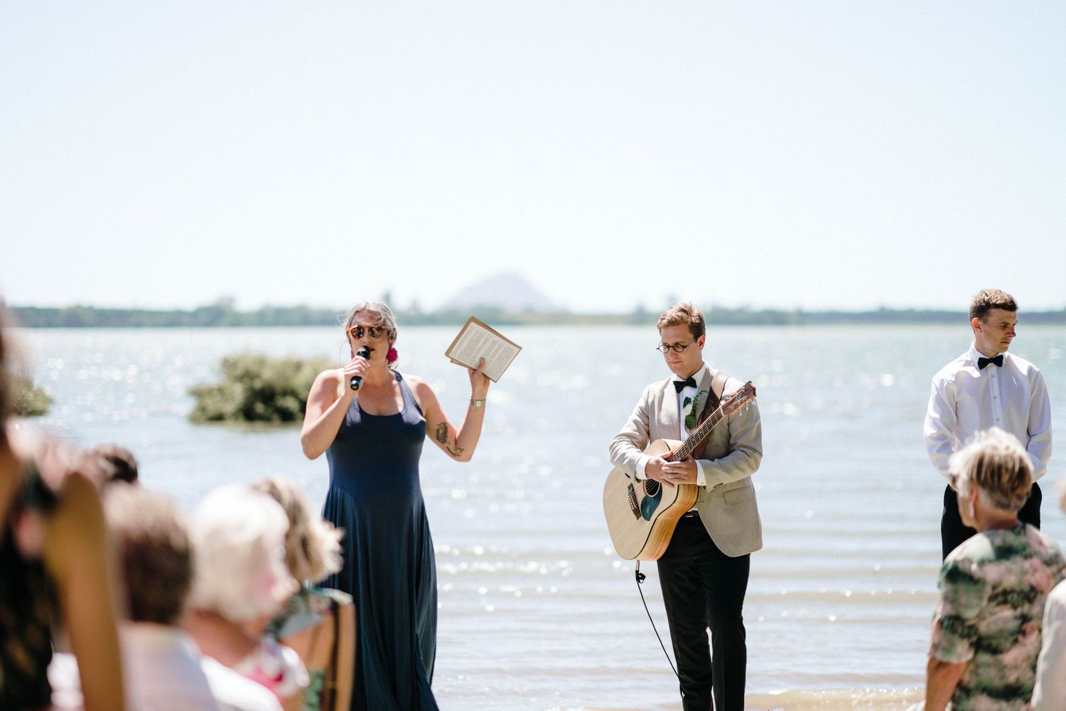 A group of people gather outdoors by a scenic waterfront for what appears to be a small event or celebration.