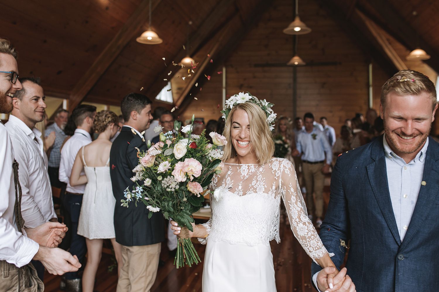 Joyful newlyweds and wedding party celebrate with laughter and dance moves in a rustic barn venue.