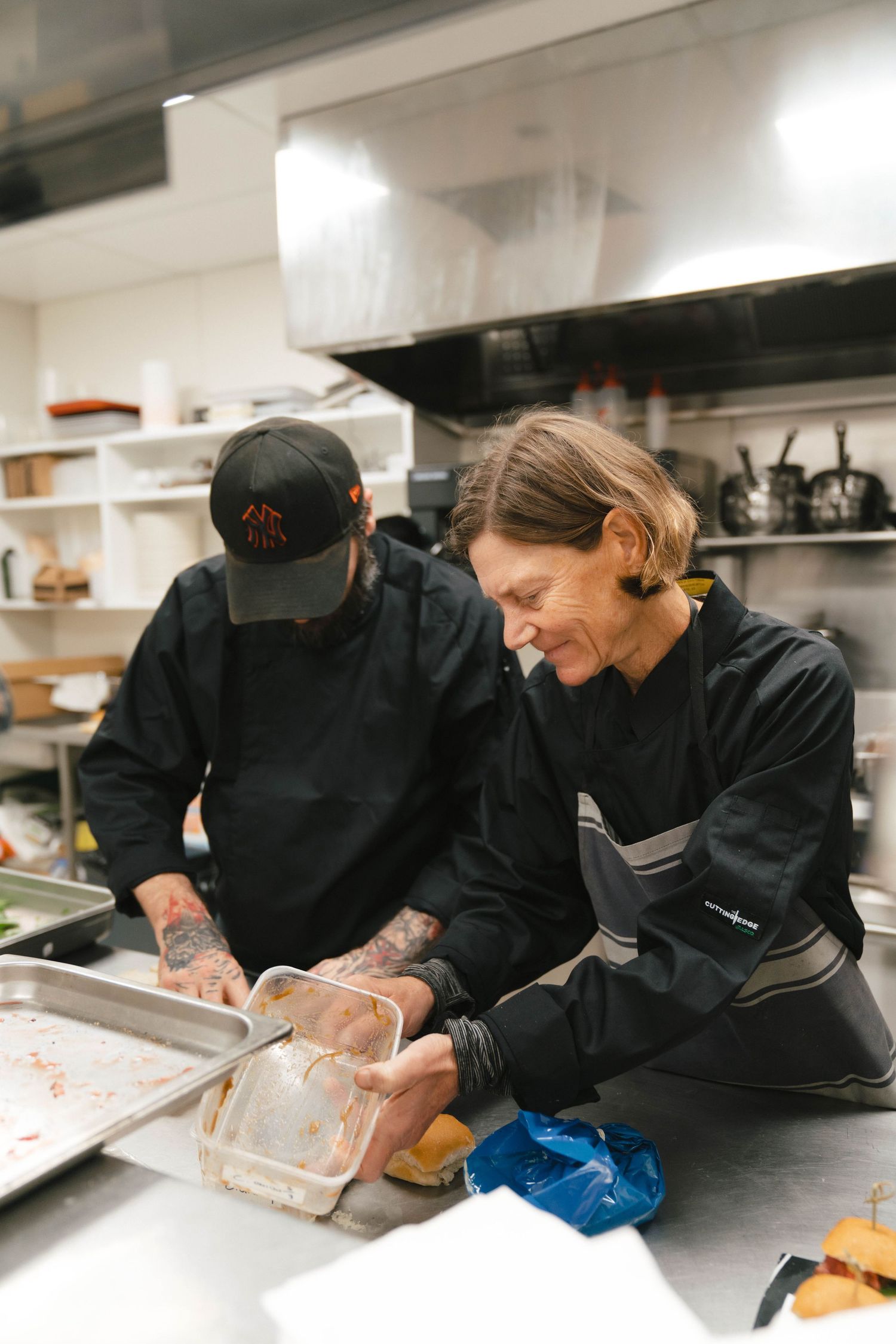 Close-up shots of figure preparing food in commercial kitchen wearing black chef coat.