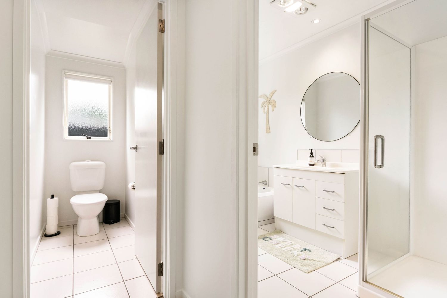 Clean white bathroom featuring modern fixtures, large mirror, and minimalist design elements.