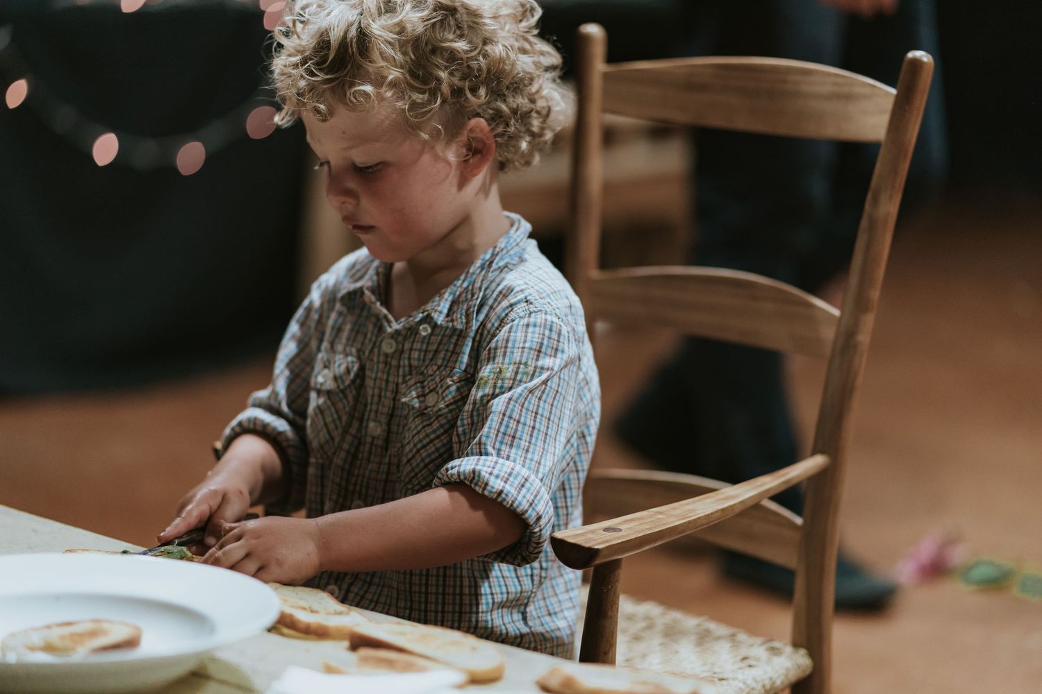 Child sitting at wooden table doing homeschool activities with books and learning materials spread out in front of them.