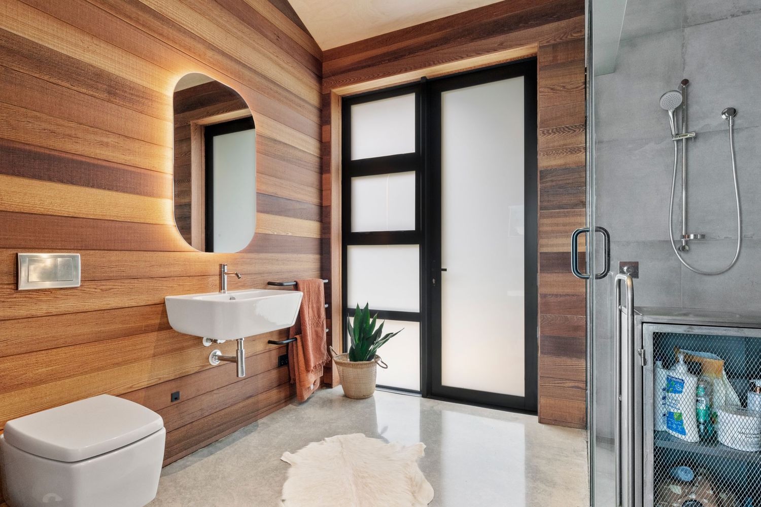 Modern bathroom interior with wooden wall panels featuring sleek fixtures, glass shower enclosure and minimalist design.