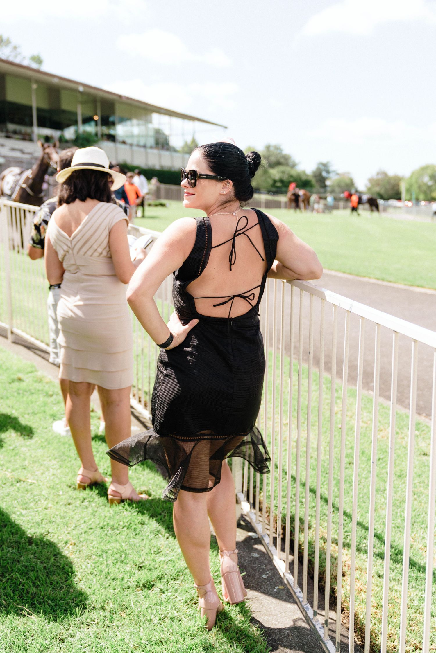People standing along a railing at an outdoor venue on a sunny day.