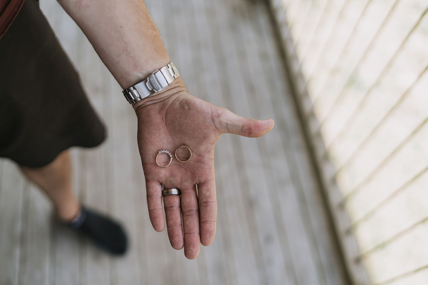 Close-up of hands holding a wedding ring against a white backdrop.