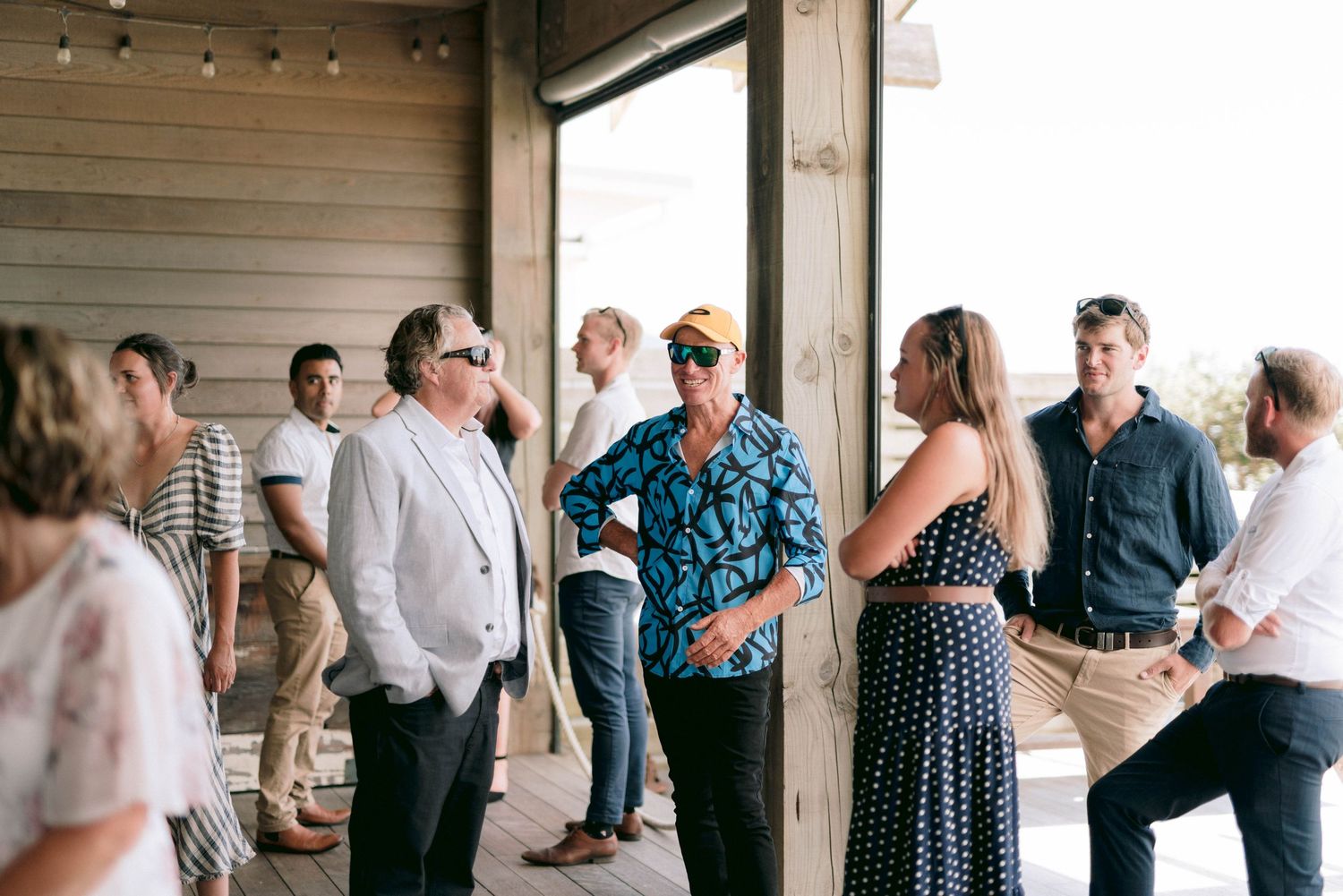 Small groups of guests mingle and chat at an informal outdoor wedding reception.