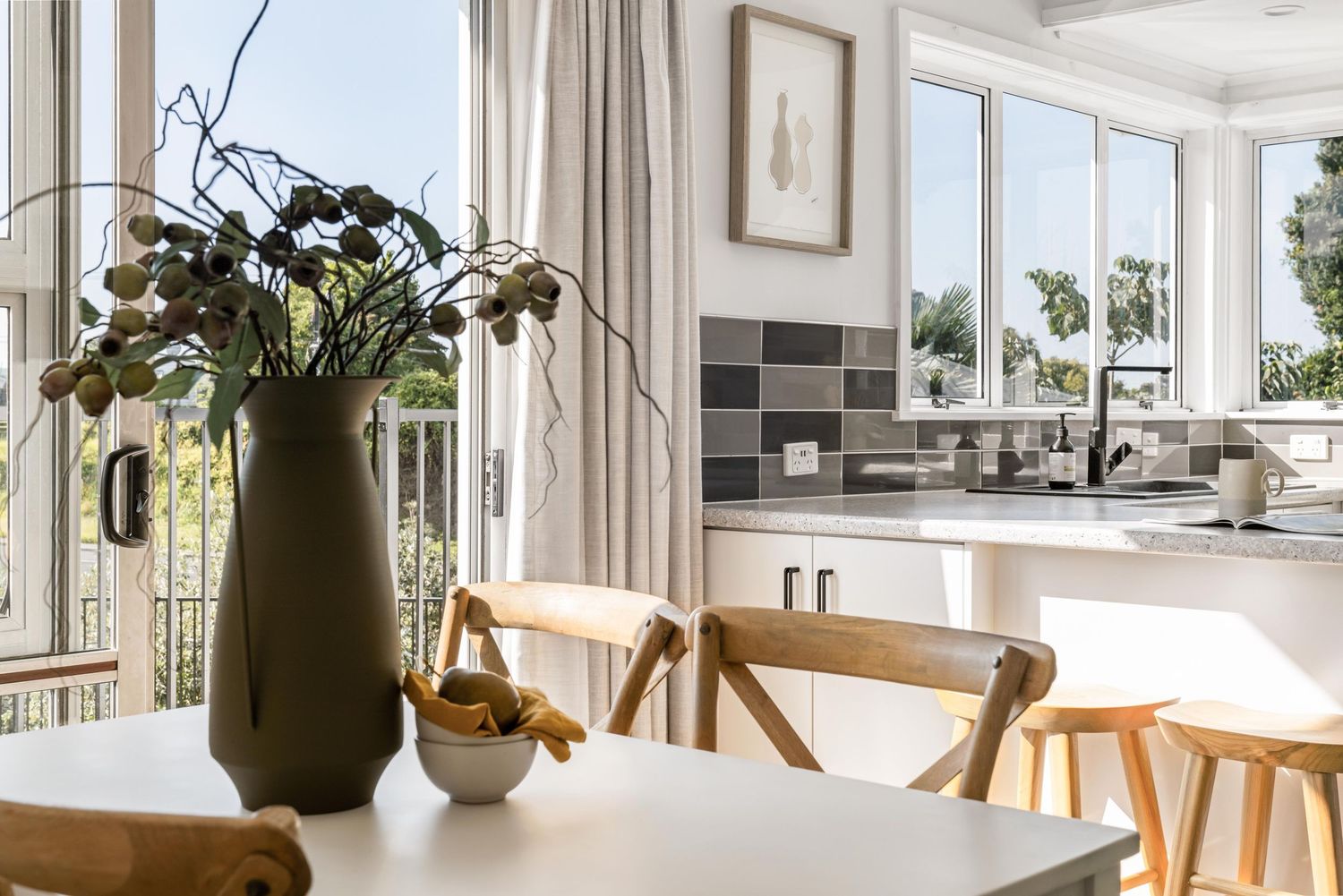 Modern open-plan dining area with large windows and kitchen view.