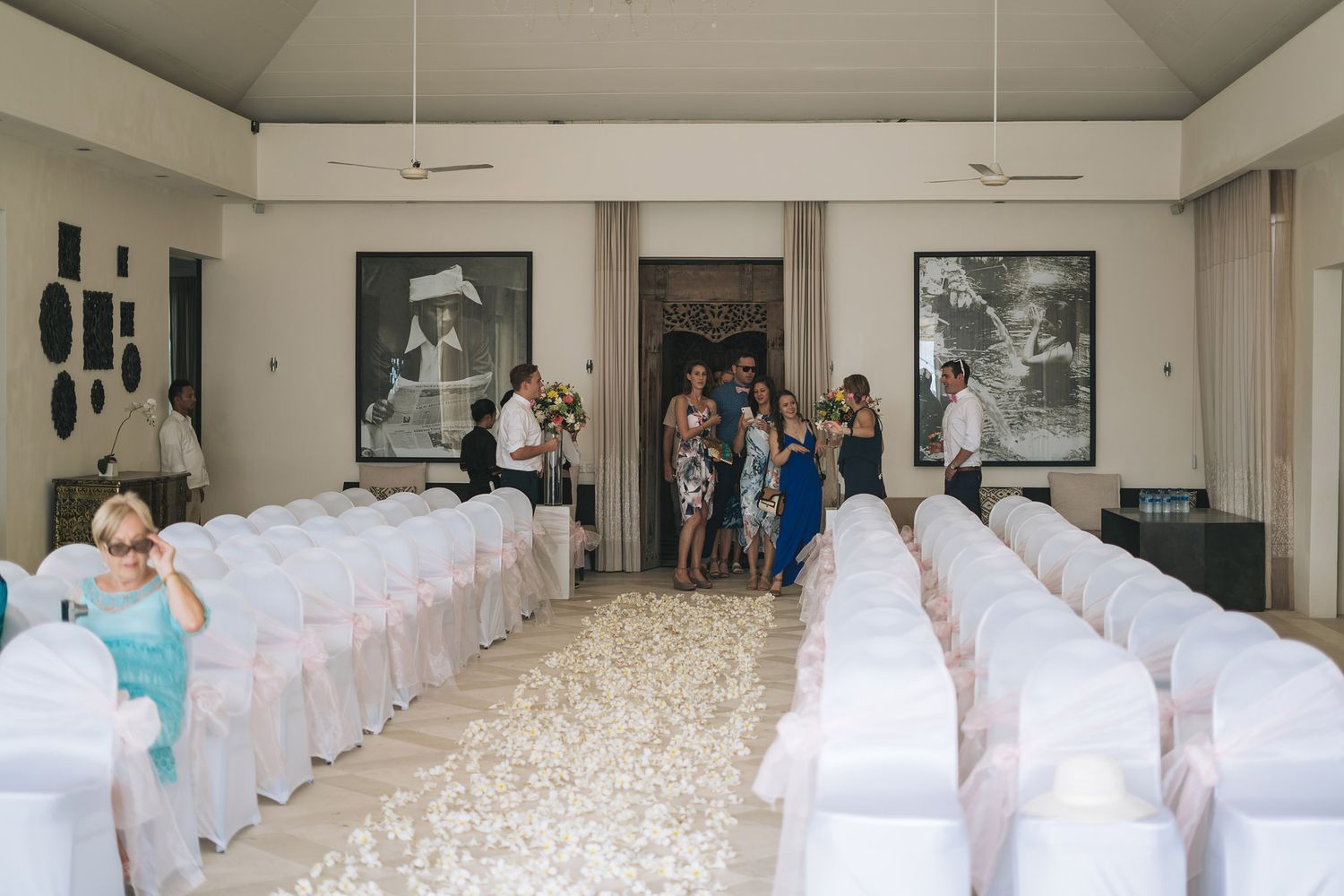 Indoor wedding reception venue with white chair covers and elegant table settings in a spacious banquet hall.