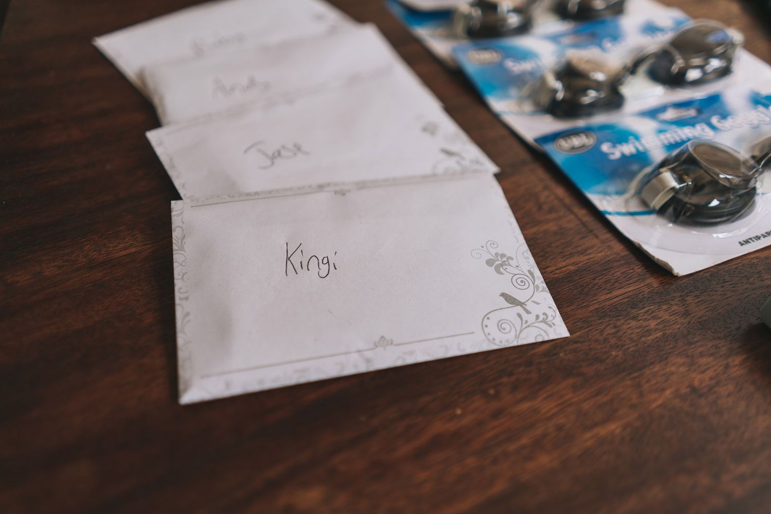 Small handwritten place cards and camera film rolls arranged on dark wooden table surface.