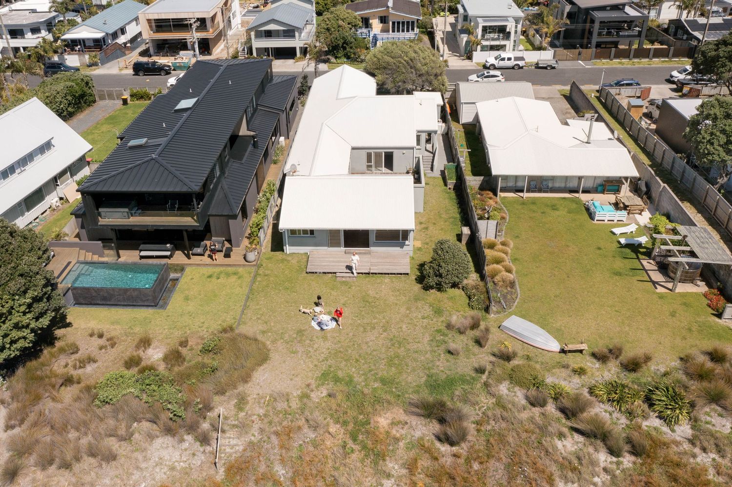 Aerial view of suburban houses and streets along a coastal neighborhood showing residential development and landscaping.