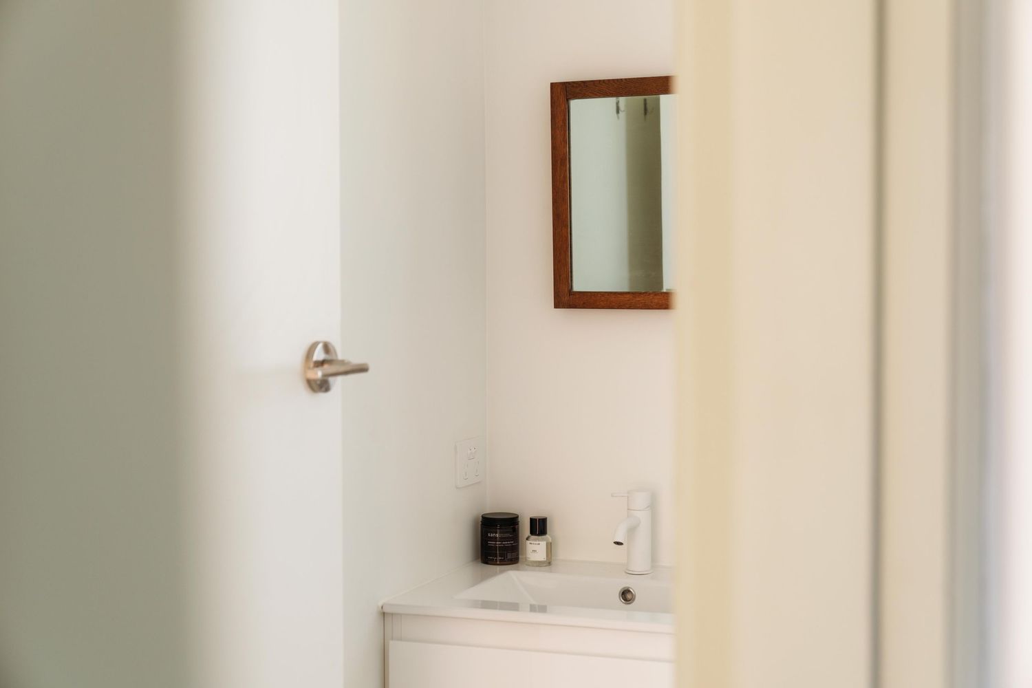 Minimalist hallway with white walls, wooden door frames, and modern light switches.