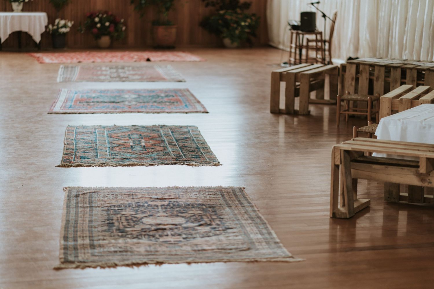 Multiple oriental rugs displayed in a gallery-like setting with hardwood floors and natural lighting.