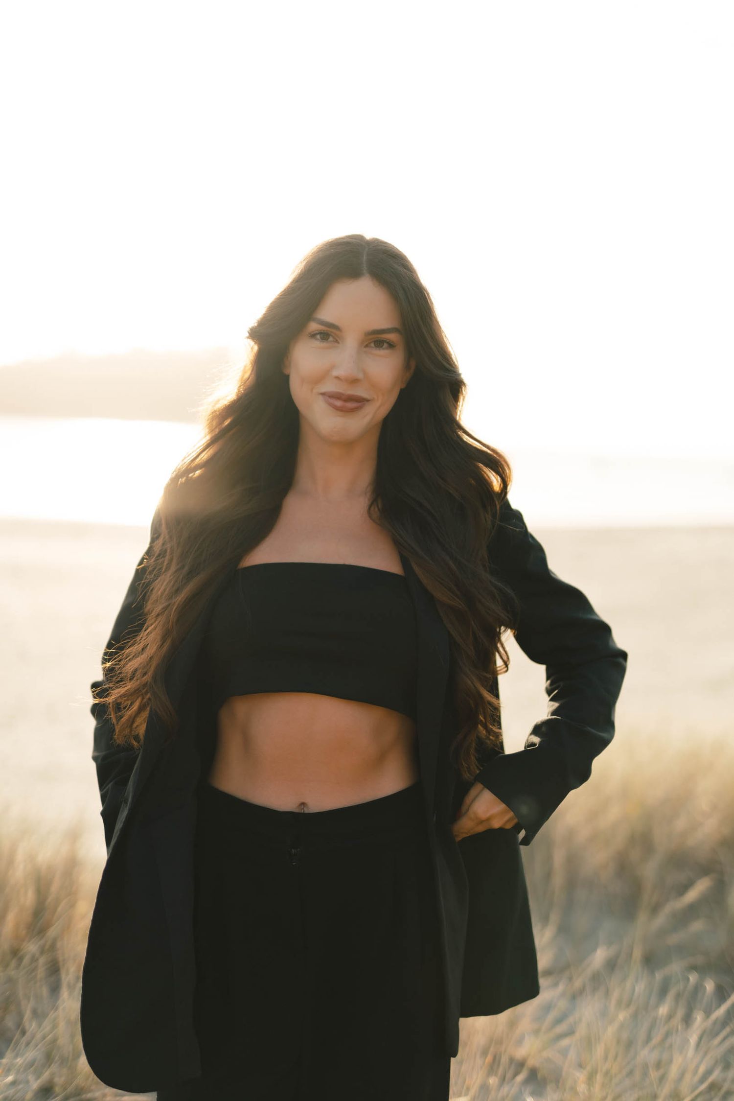 Natural light portrait featuring modern black outfit with crop top and blazer.