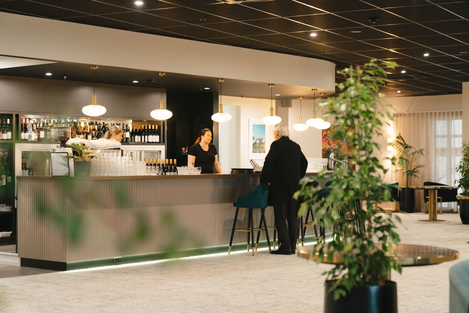 Modern office interior with sleek lighting design features exposed black ceiling and minimalist workspaces.