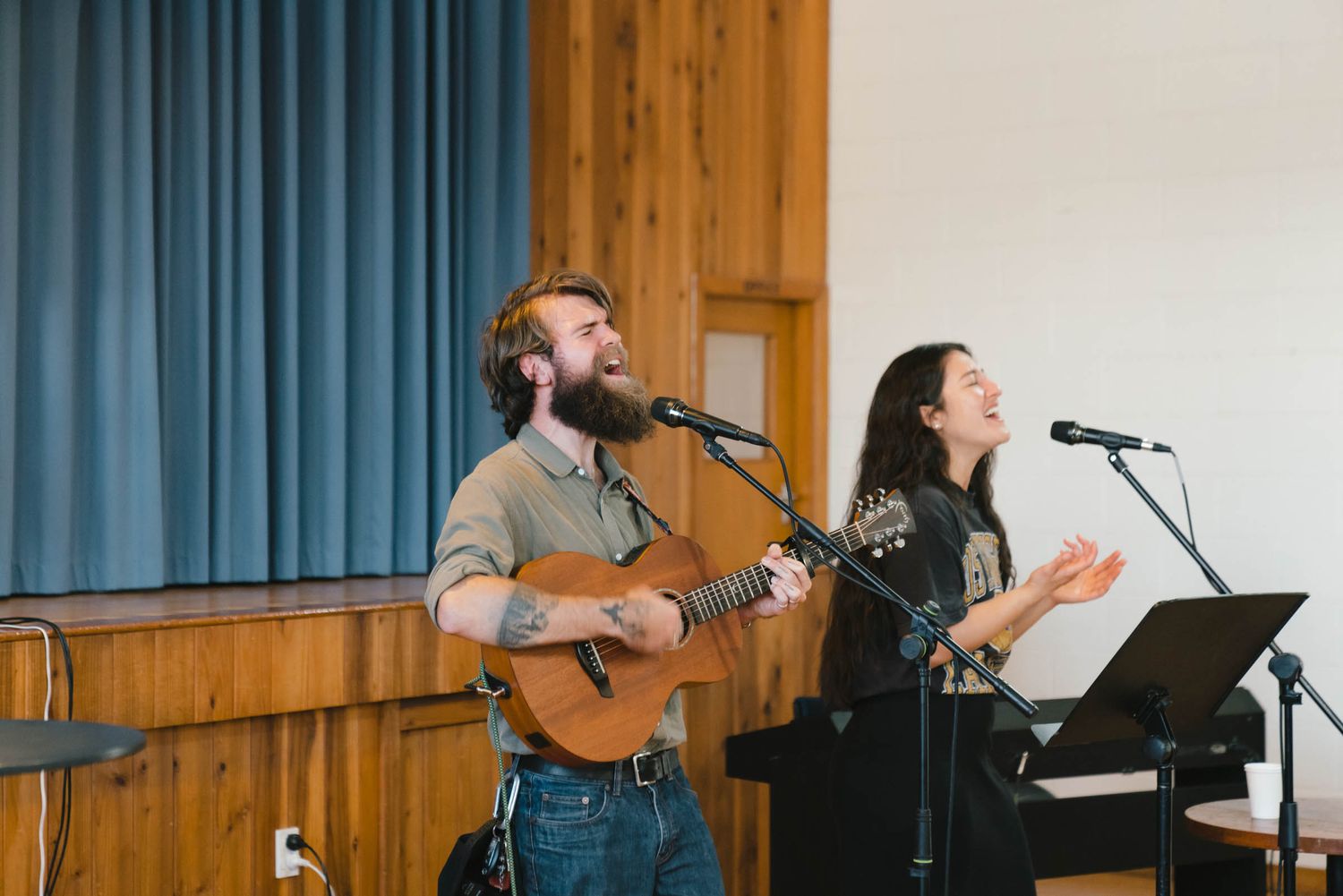 Musicians leading worship with guitars and microphones on a church stage.