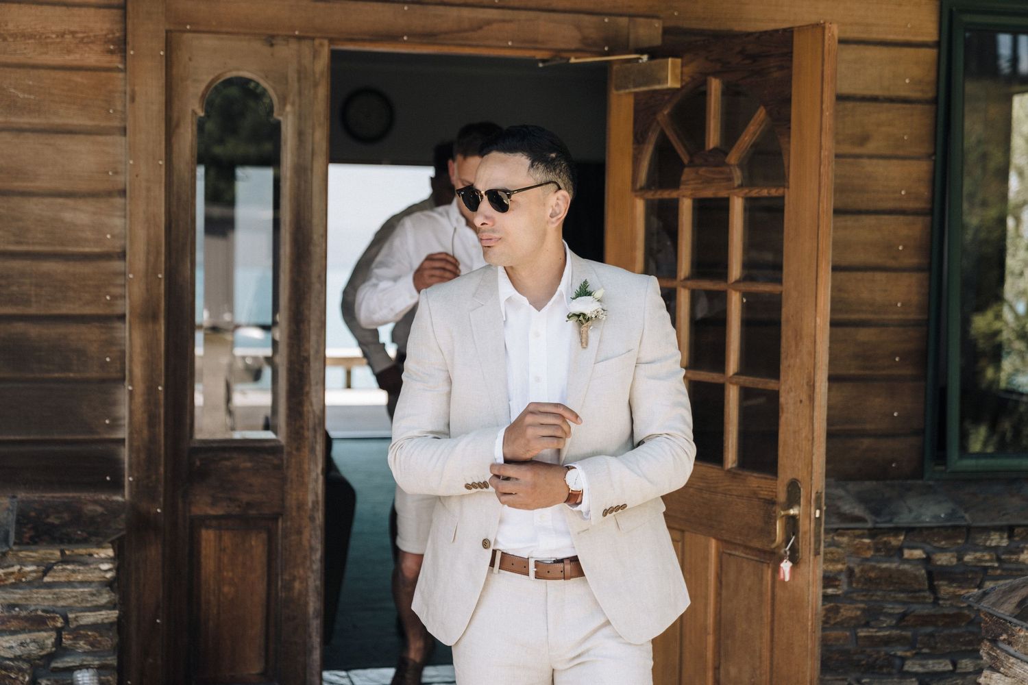 Elegant couple in matching white outfits sharing a romantic moment on a rustic wooden porch.