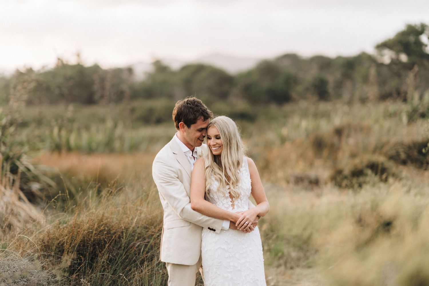 A couple shares an intimate moment together in a rustic field setting at sunset.