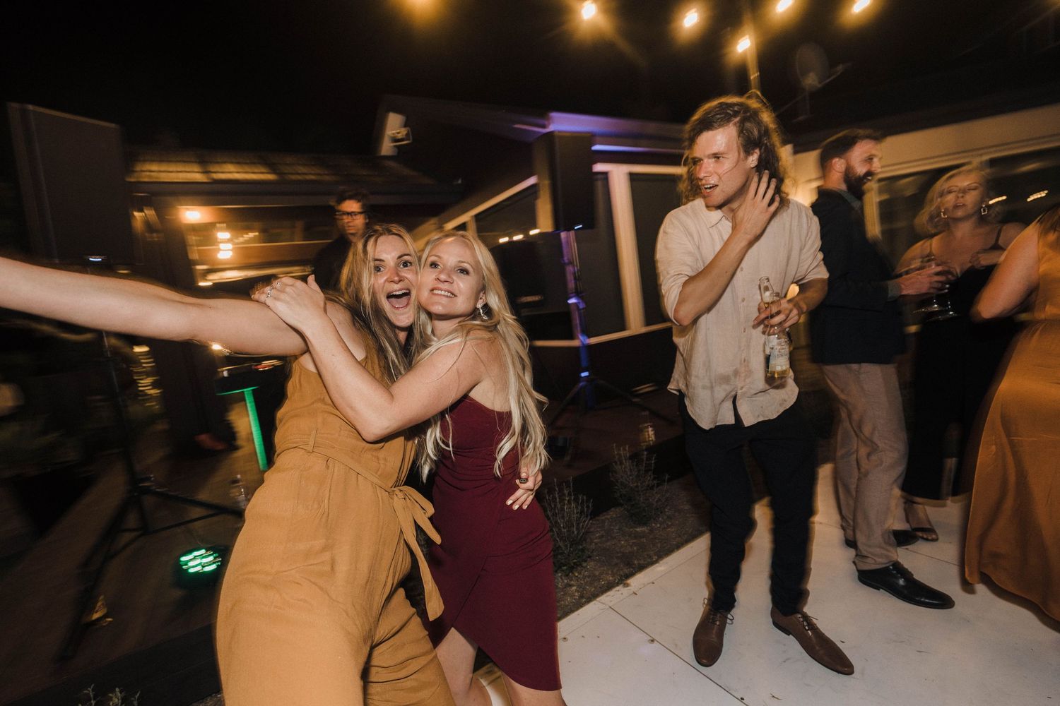 People dancing and enjoying themselves at a nighttime party with warm lighting and festive atmosphere.