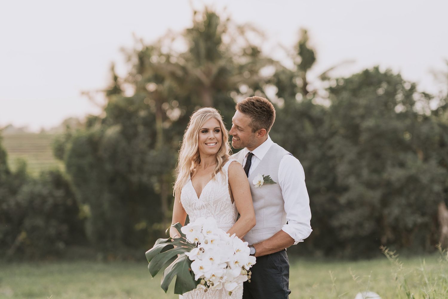 Newlyweds sharing intimate moments in an outdoor garden setting.