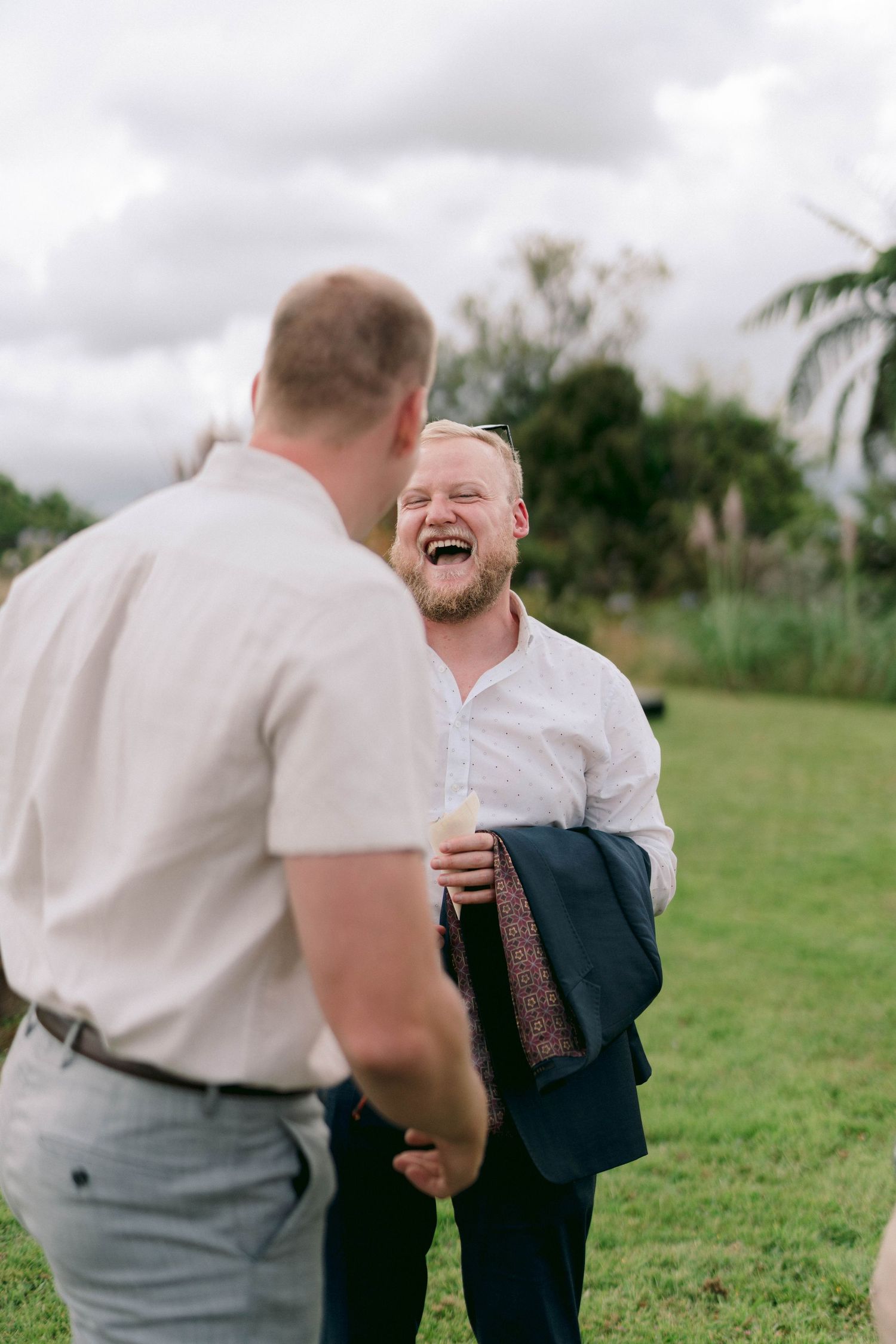 Two guests share a laugh during outdoor wedding celebration.