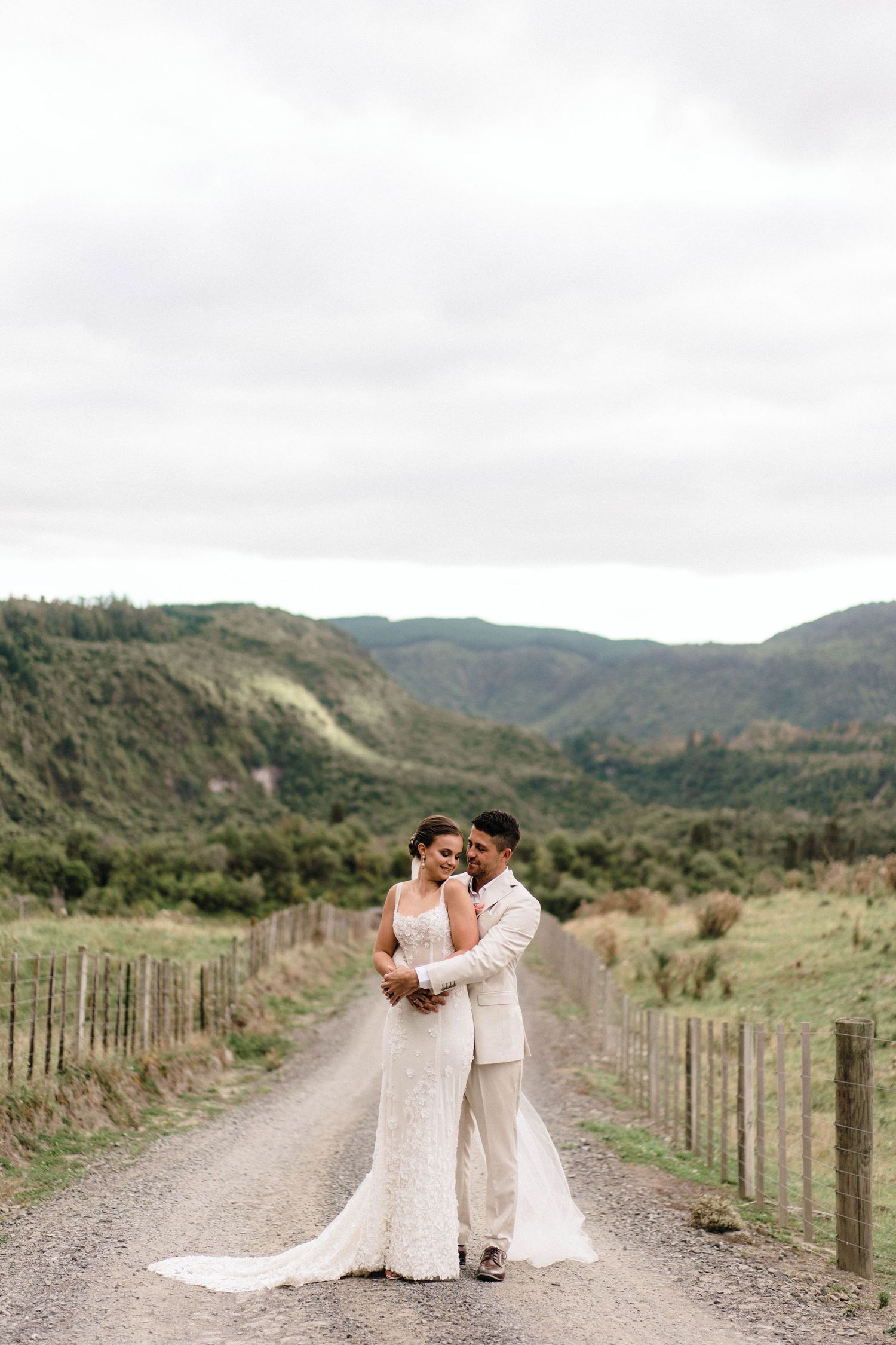 Romantic couple embracing on a country road with scenic mountain backdrop.