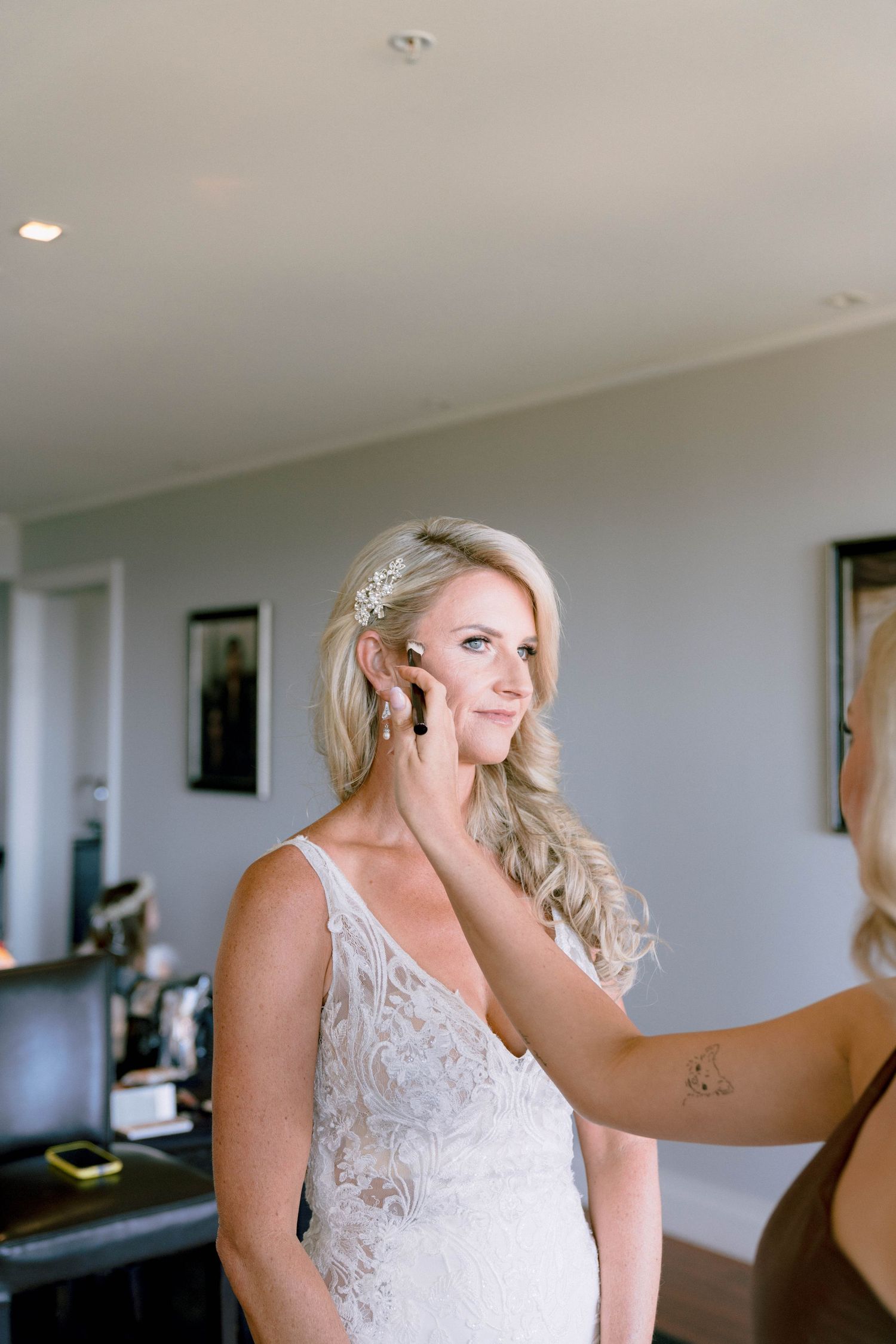 Final touches being applied to bridal hair and makeup in an elegant getting ready room.