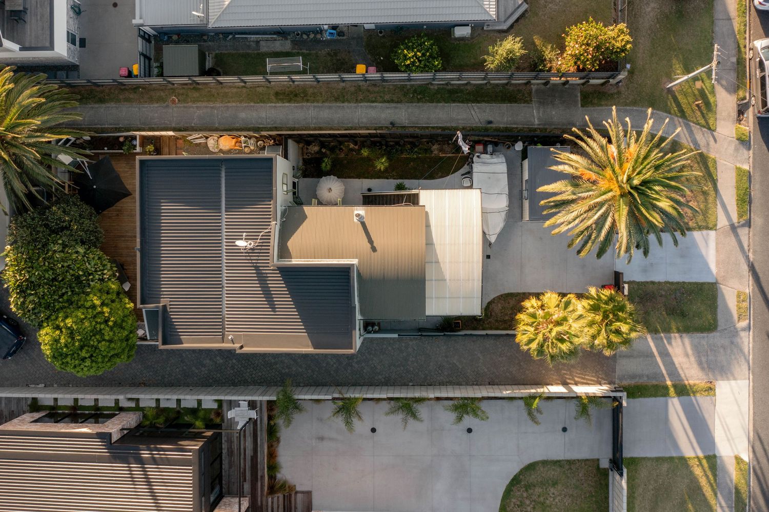 Aerial view of a residential house rooftop with solar panels and surrounding garden landscaping.