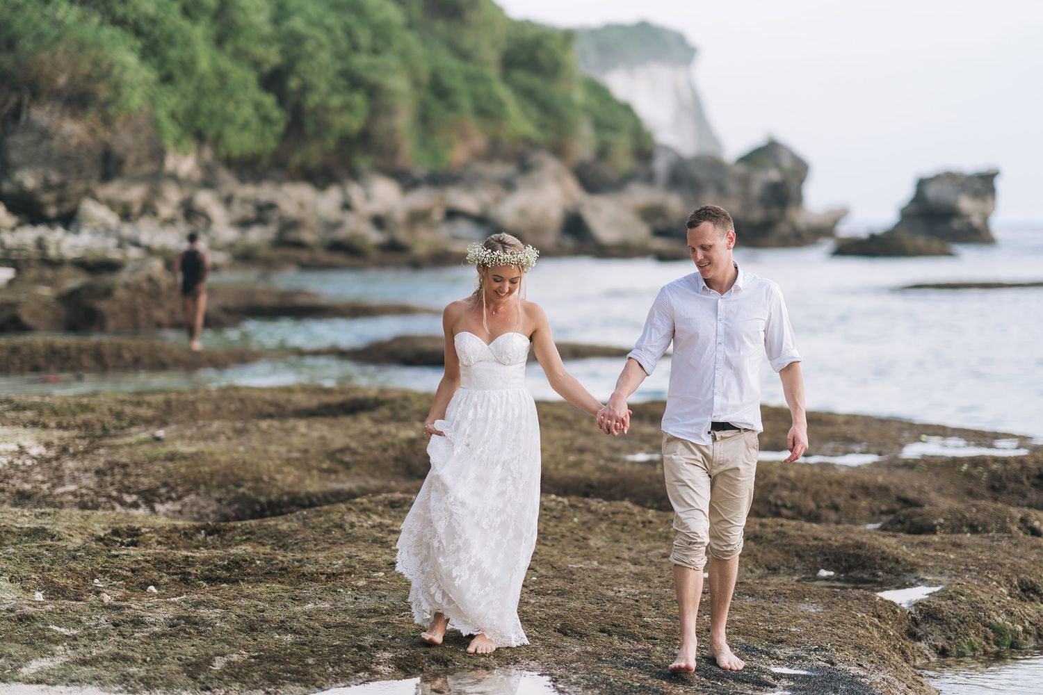 Wedding photo shoot on a scenic rocky beach with natural cliffs and ocean views.