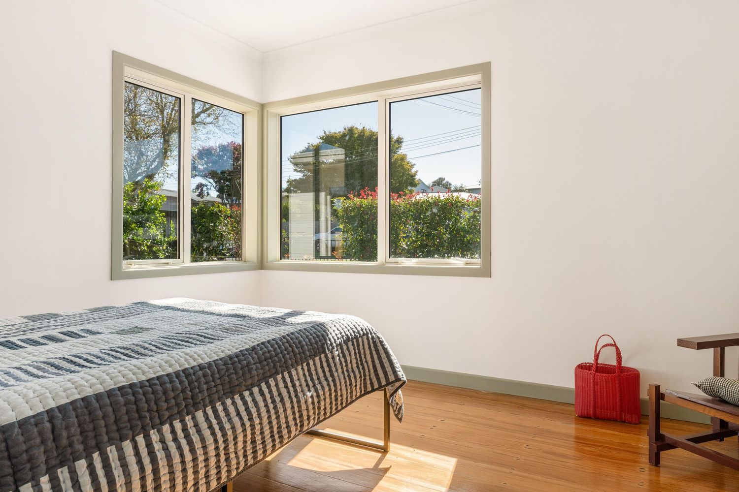 Bright bedroom with large windows offering natural light and a single red accent chair.