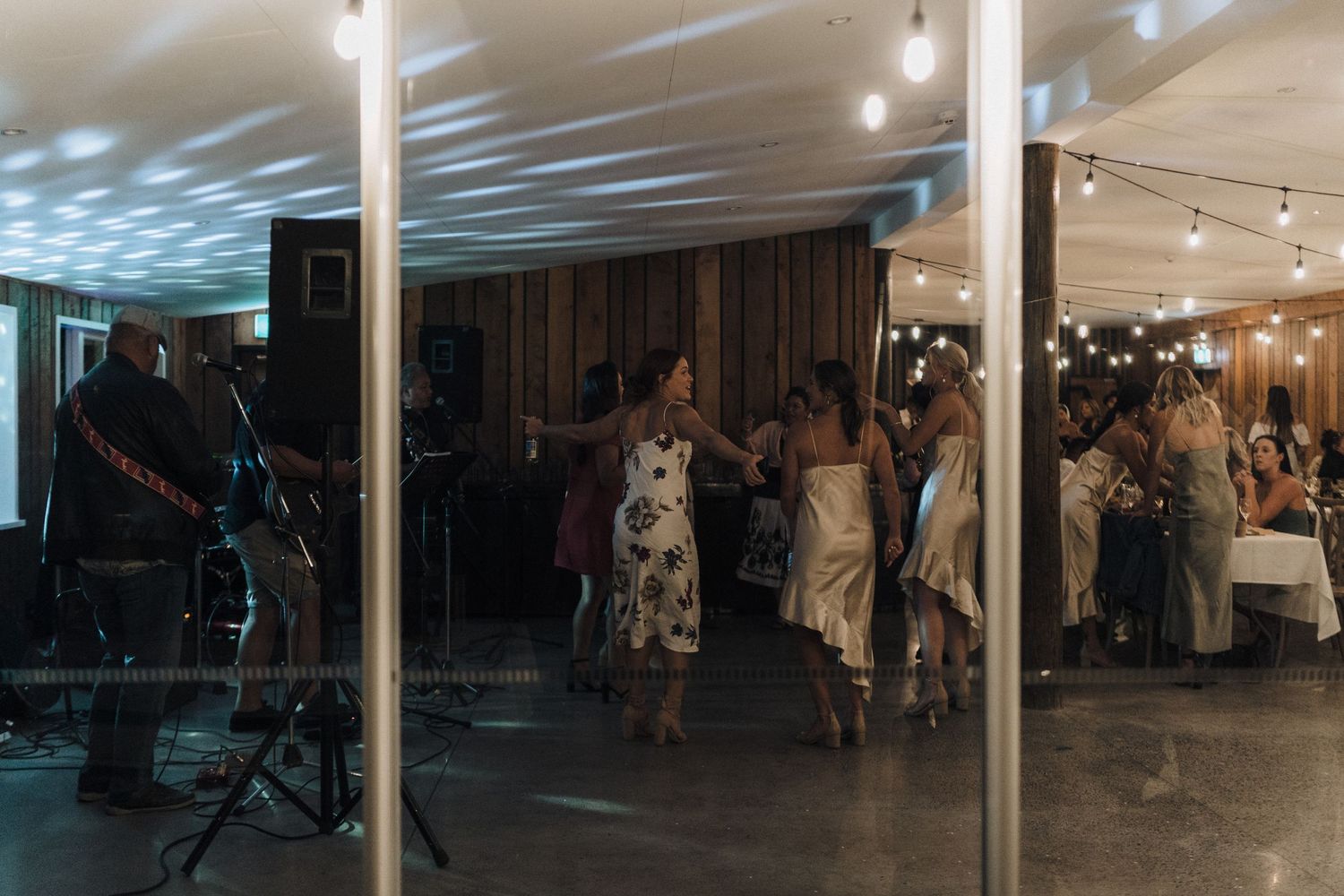 Silhouettes of wedding guests dancing at an evening reception with dramatic lighting.
