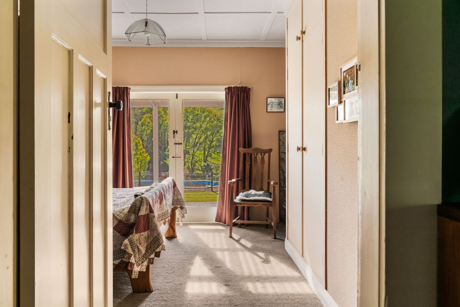 Sunlit hallway interior with wooden floors and mountain views through windows.