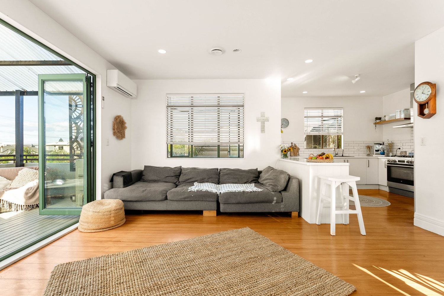 Bright living space with gray sectional sofa, jute rug, and large sliding glass doors opening to balcony.