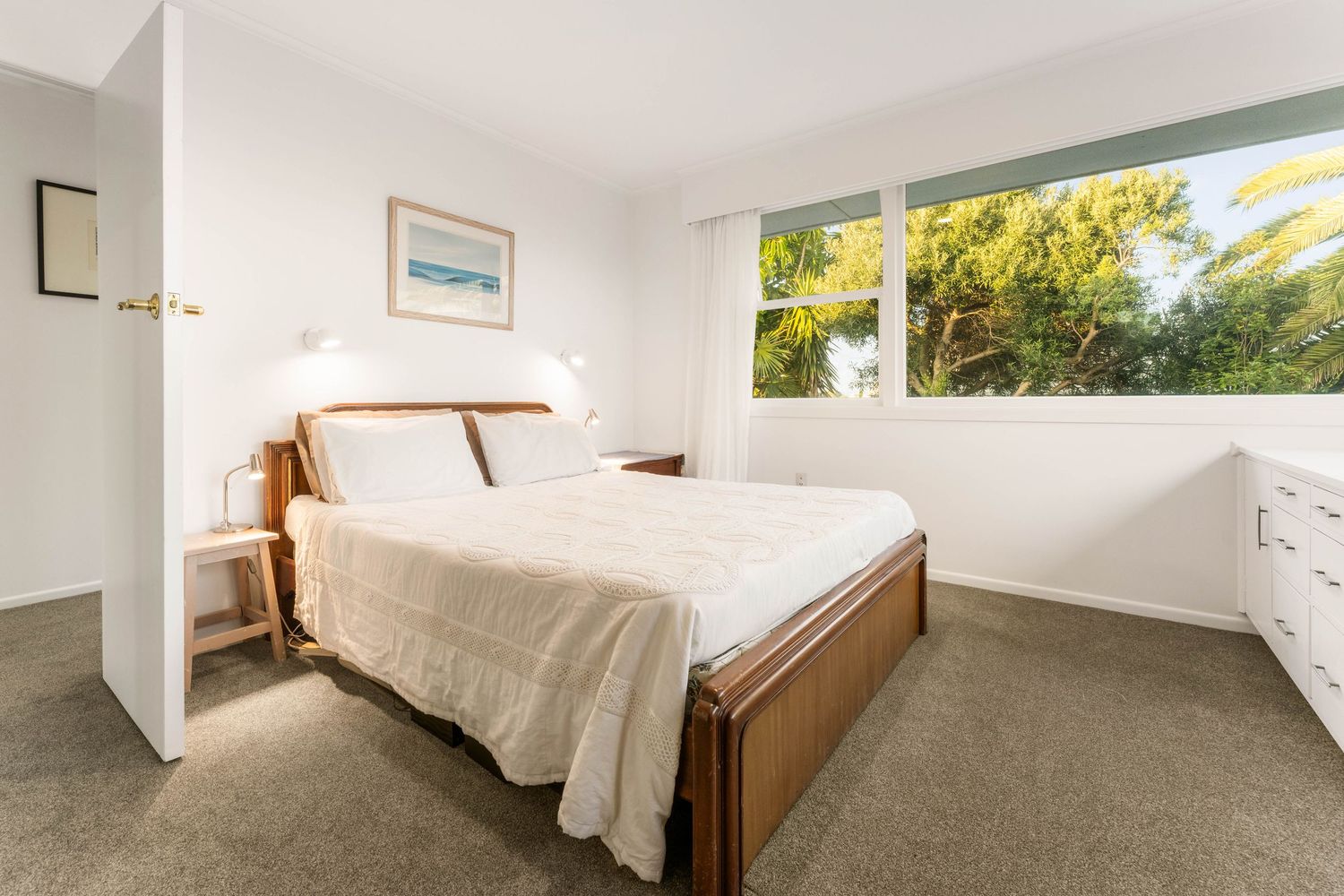 Spacious bedroom with white linens and large windows allowing natural light to flood the space.
