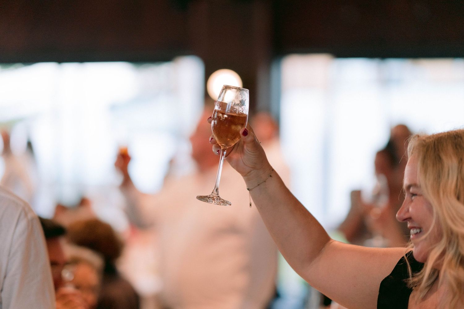 A group raises wine glasses in a celebratory toast at what appears to be a festive indoor gathering.