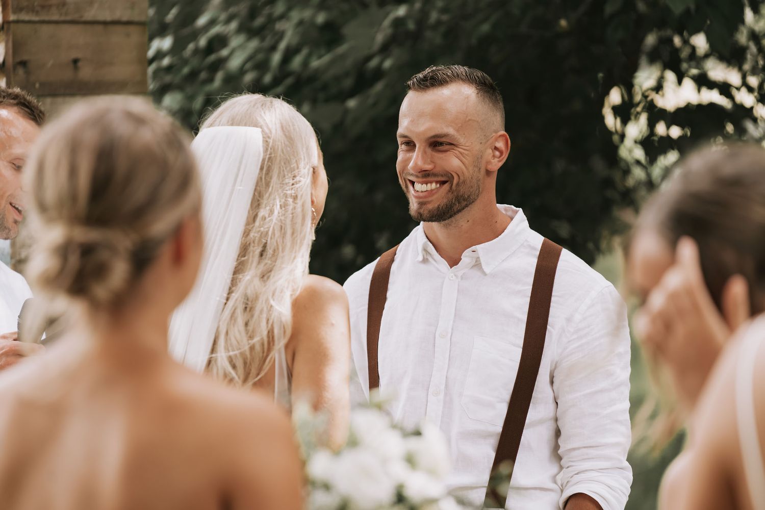 A joyful outdoor wedding scene in neutral tones with guests gathering and socializing at round tables.