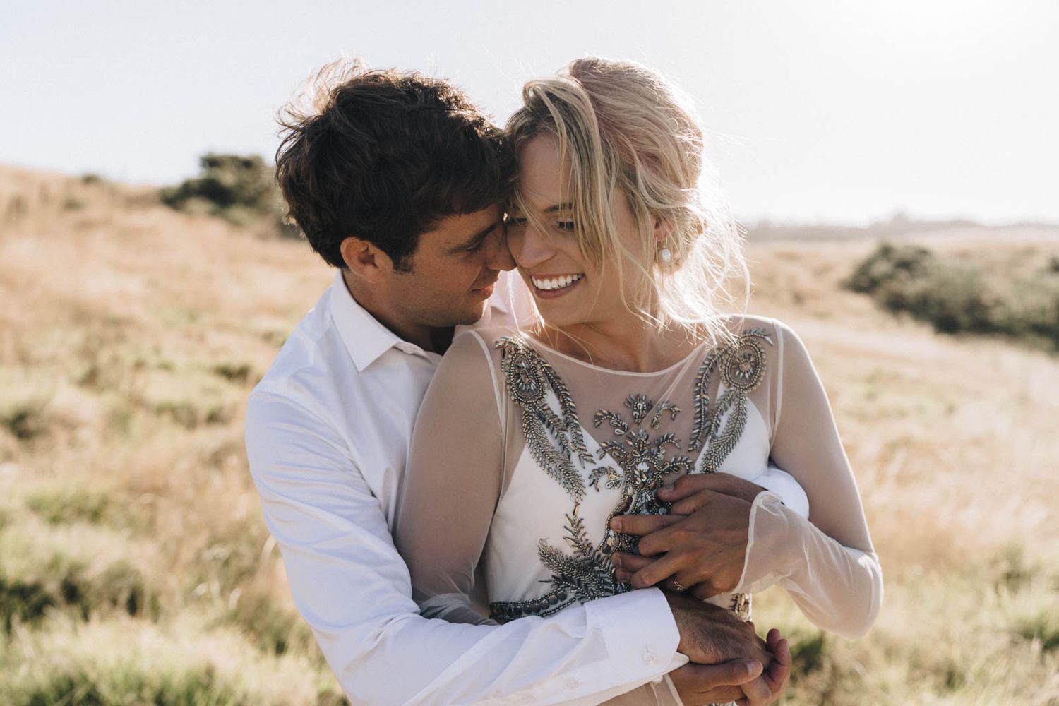 Romantic couple shares tender moments in sunlit desert landscape series of candid wedding photos.