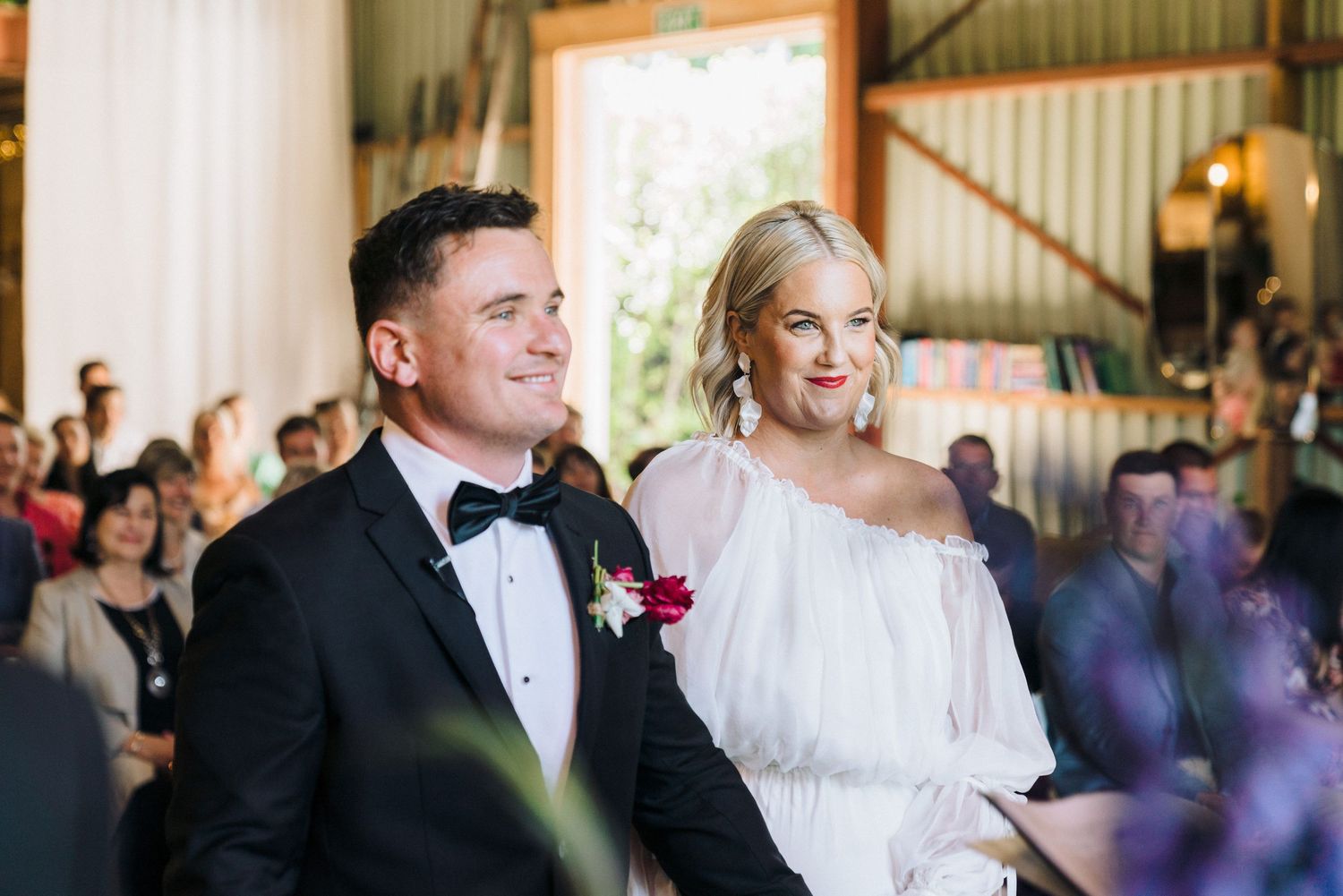 A formal wedding ceremony setting with guests seated in a rustic barn venue.