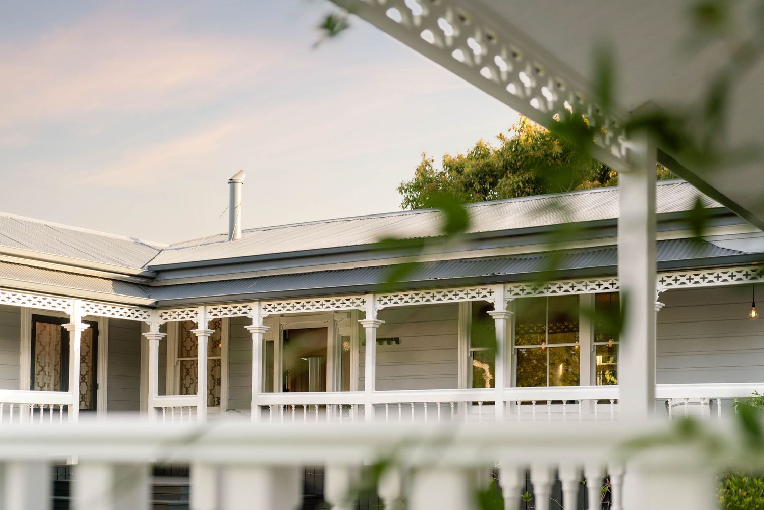 Elegant white porch detail with decorative columns and lattice trim along the roofline.