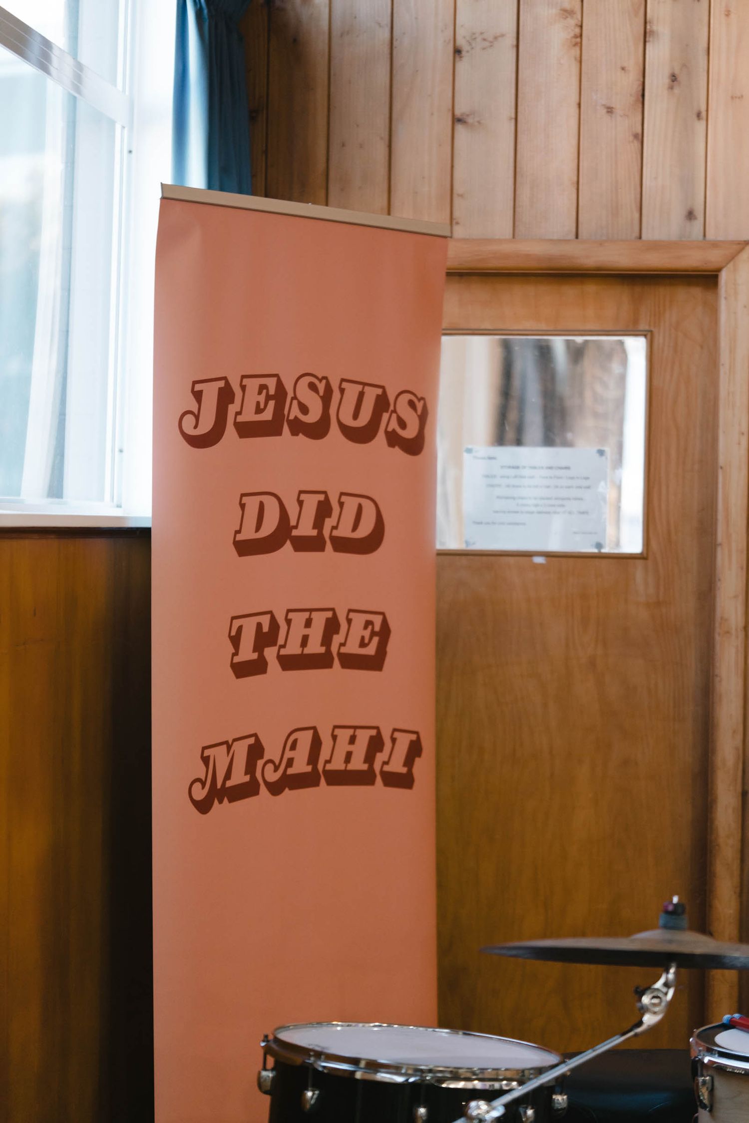 An orange banner with text reading 'JESUS DID THE REAL' displayed next to wooden paneling.