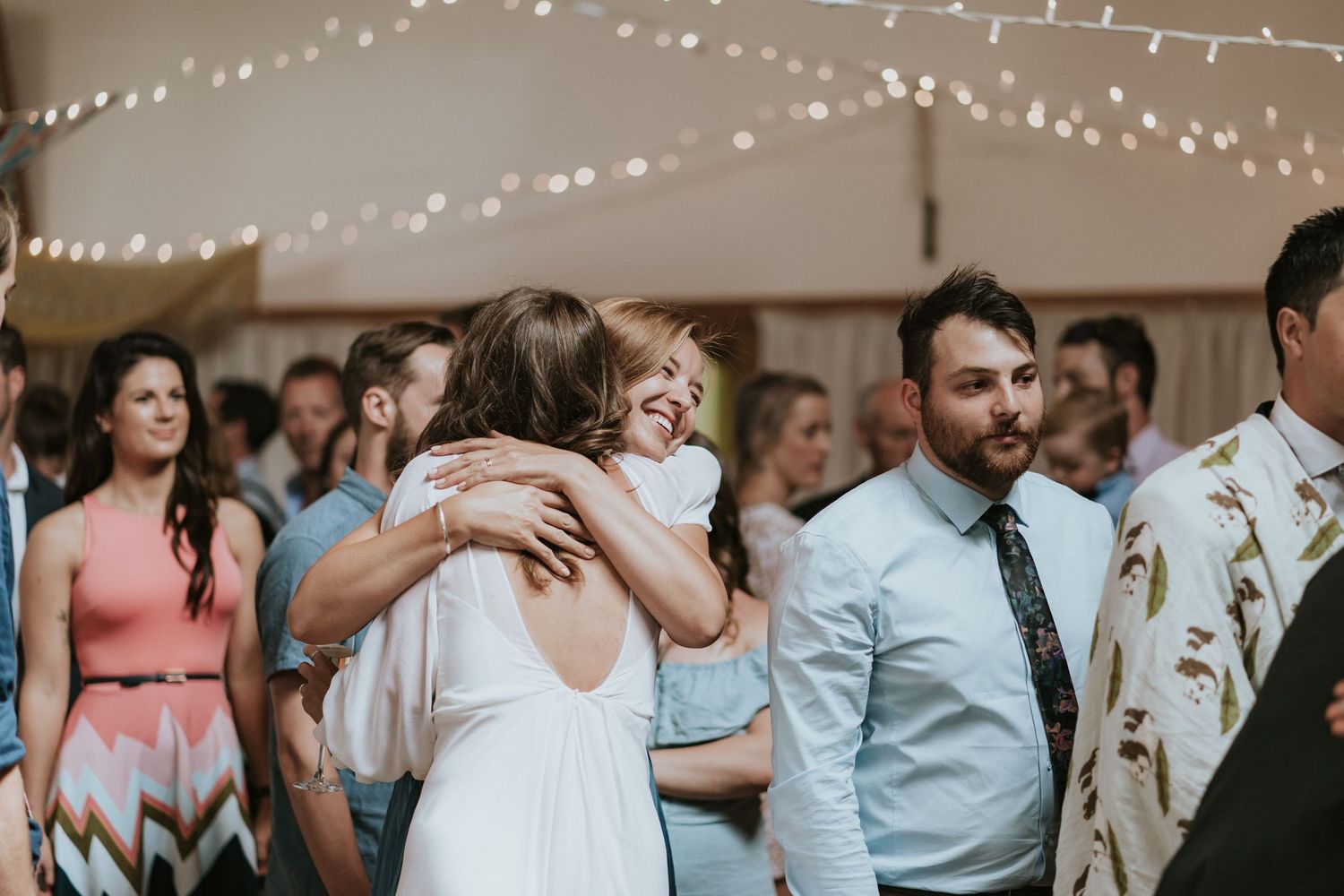 Wedding guests form a circle holding hands and dancing together during a joyous celebration at a reception.