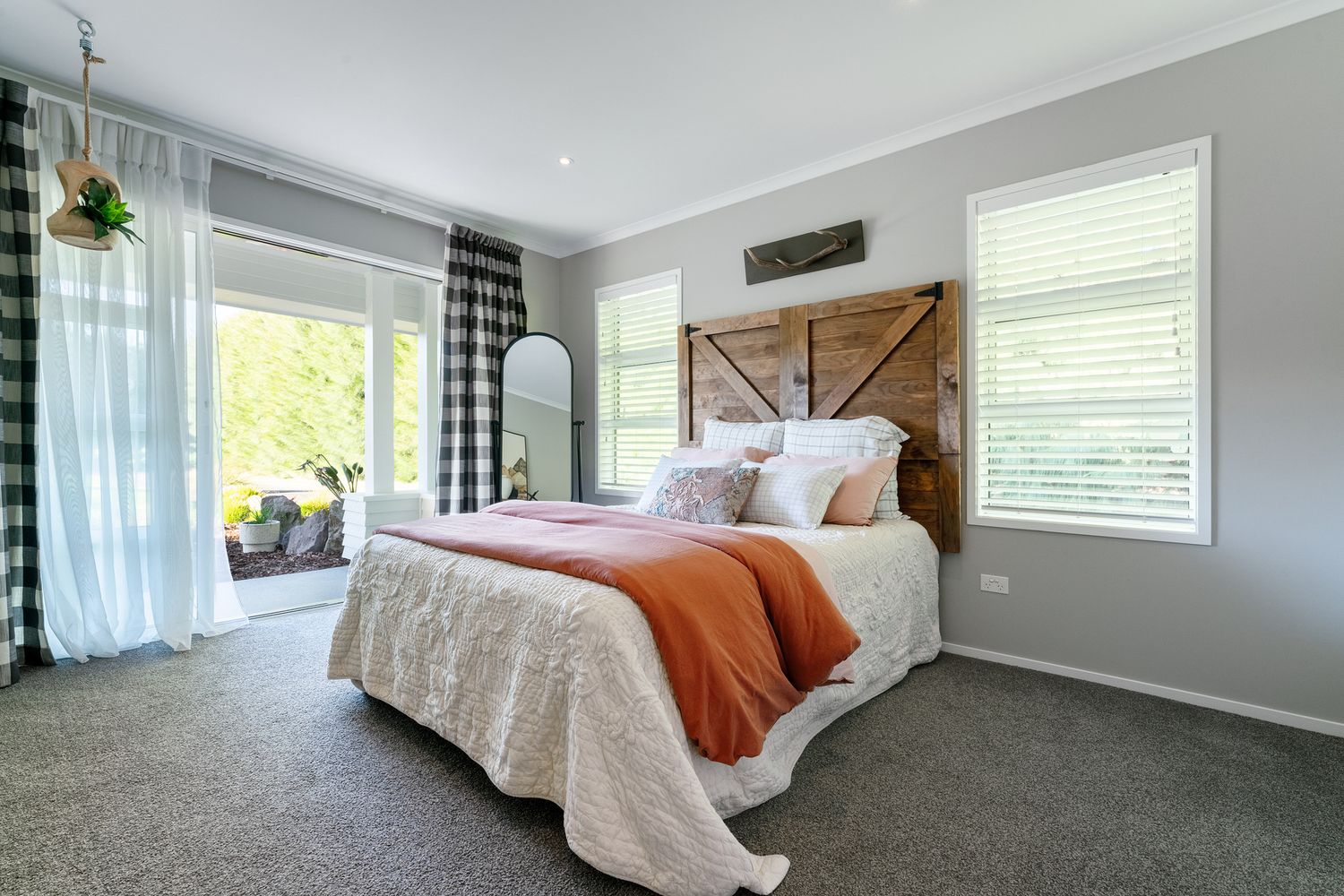 Large bedroom with grey carpet, plaid curtains and comfortable bedding.