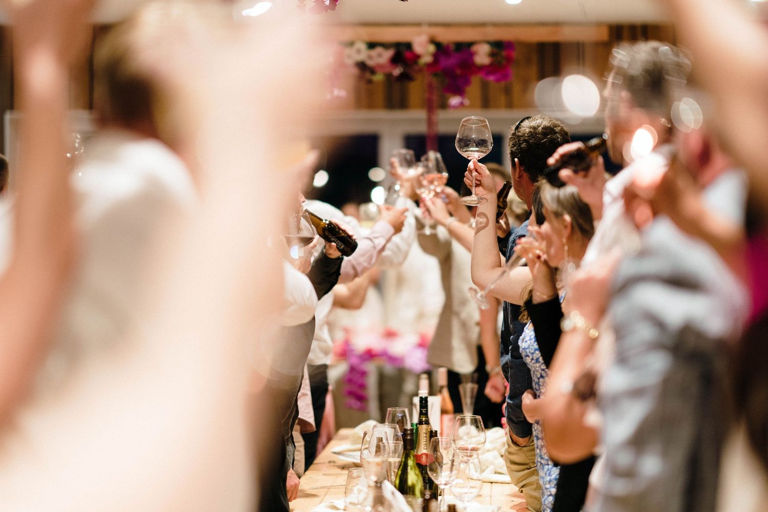 Wedding reception guests raising champagne glasses in celebration at a festive dinner table.
