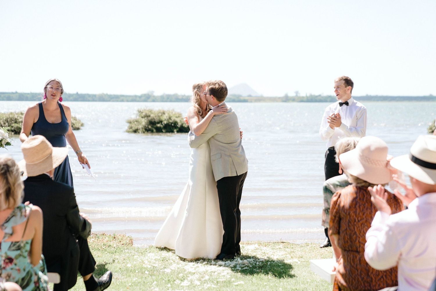 Seaside celebration with guests gathered on a sunny beach setting.