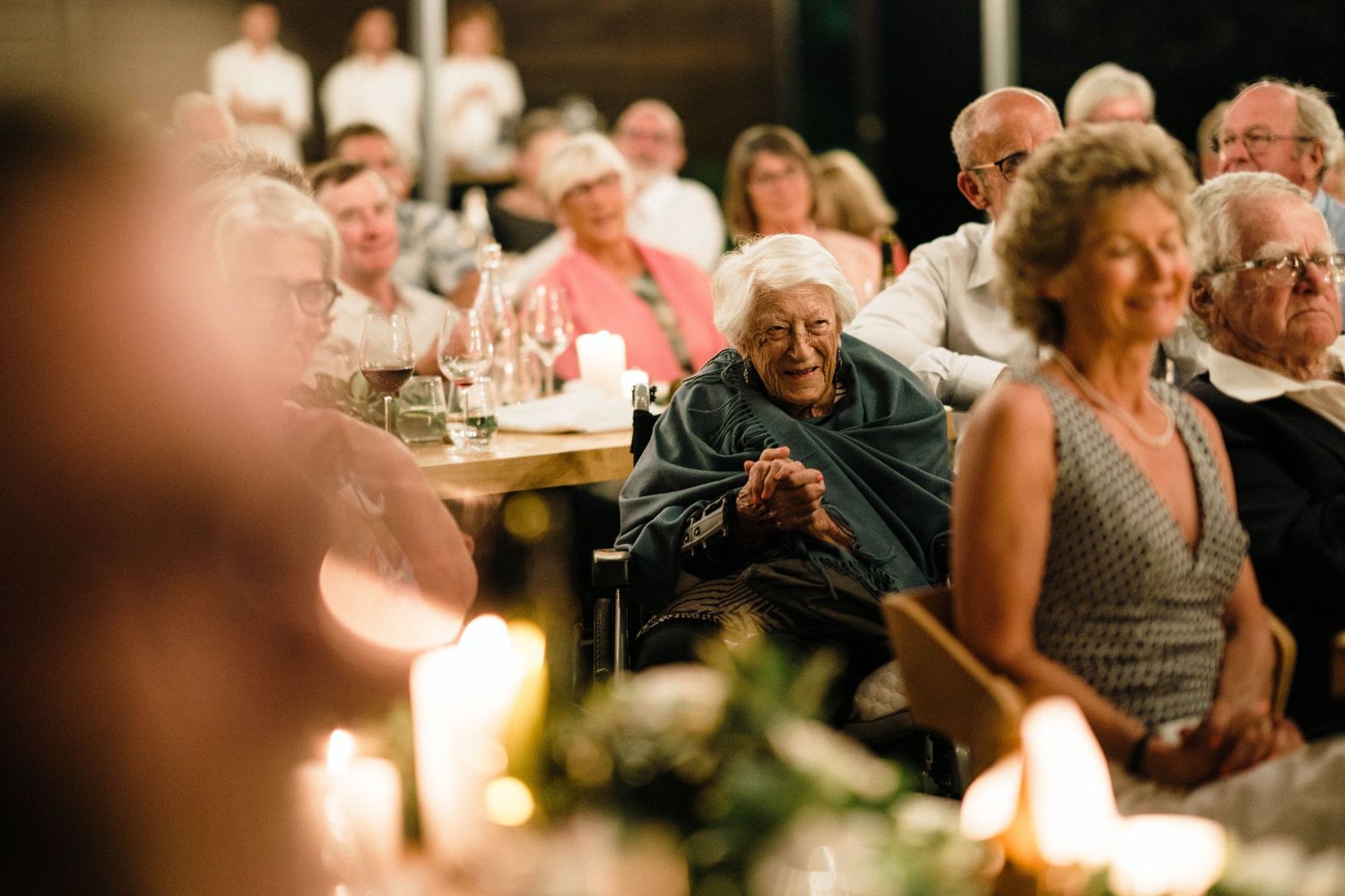 Wedding guests seated at candlelit tables during an evening reception.