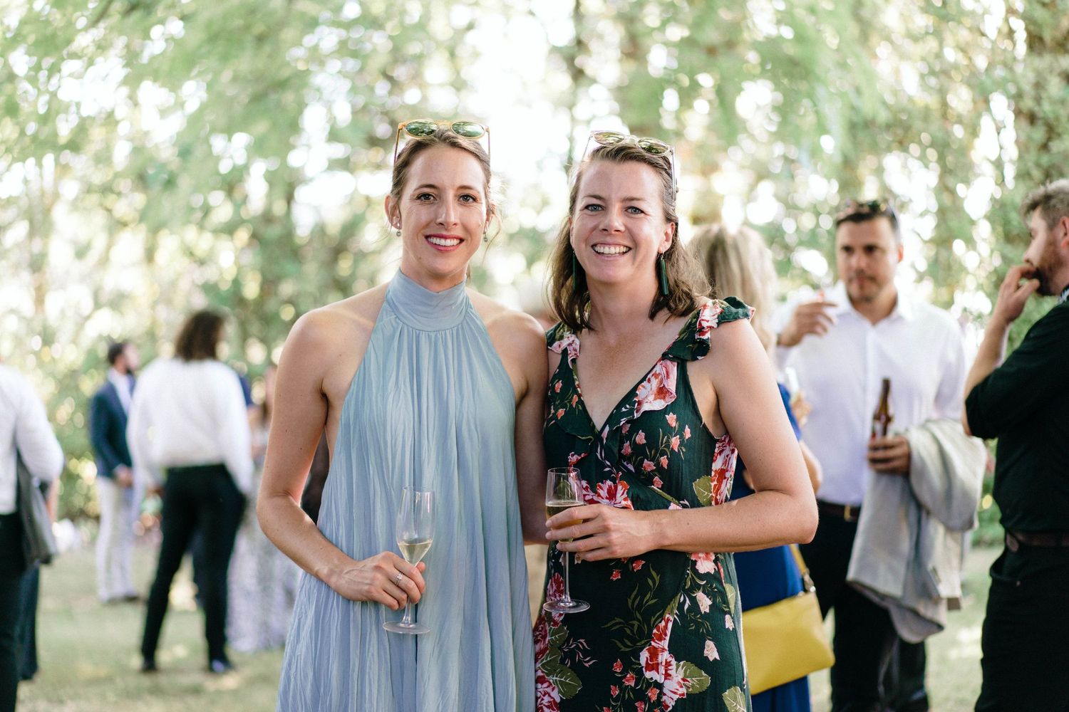 Wedding guests in summer attire mingling at an outdoor celebration.