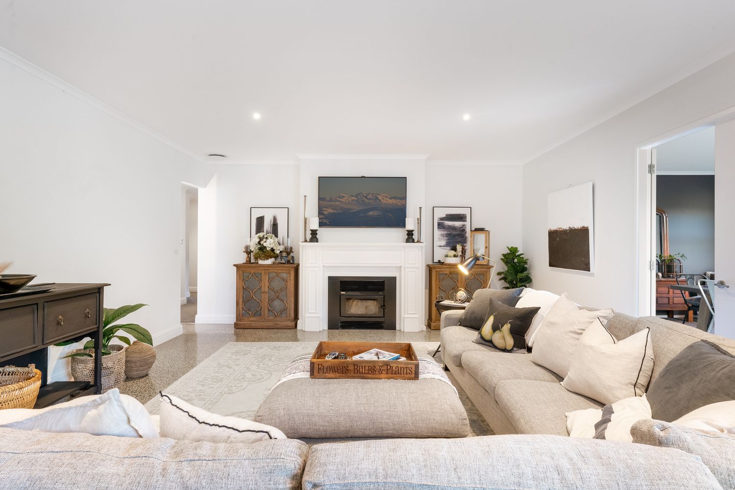 Open concept living room with neutral decor, plush seating and modern fireplace.